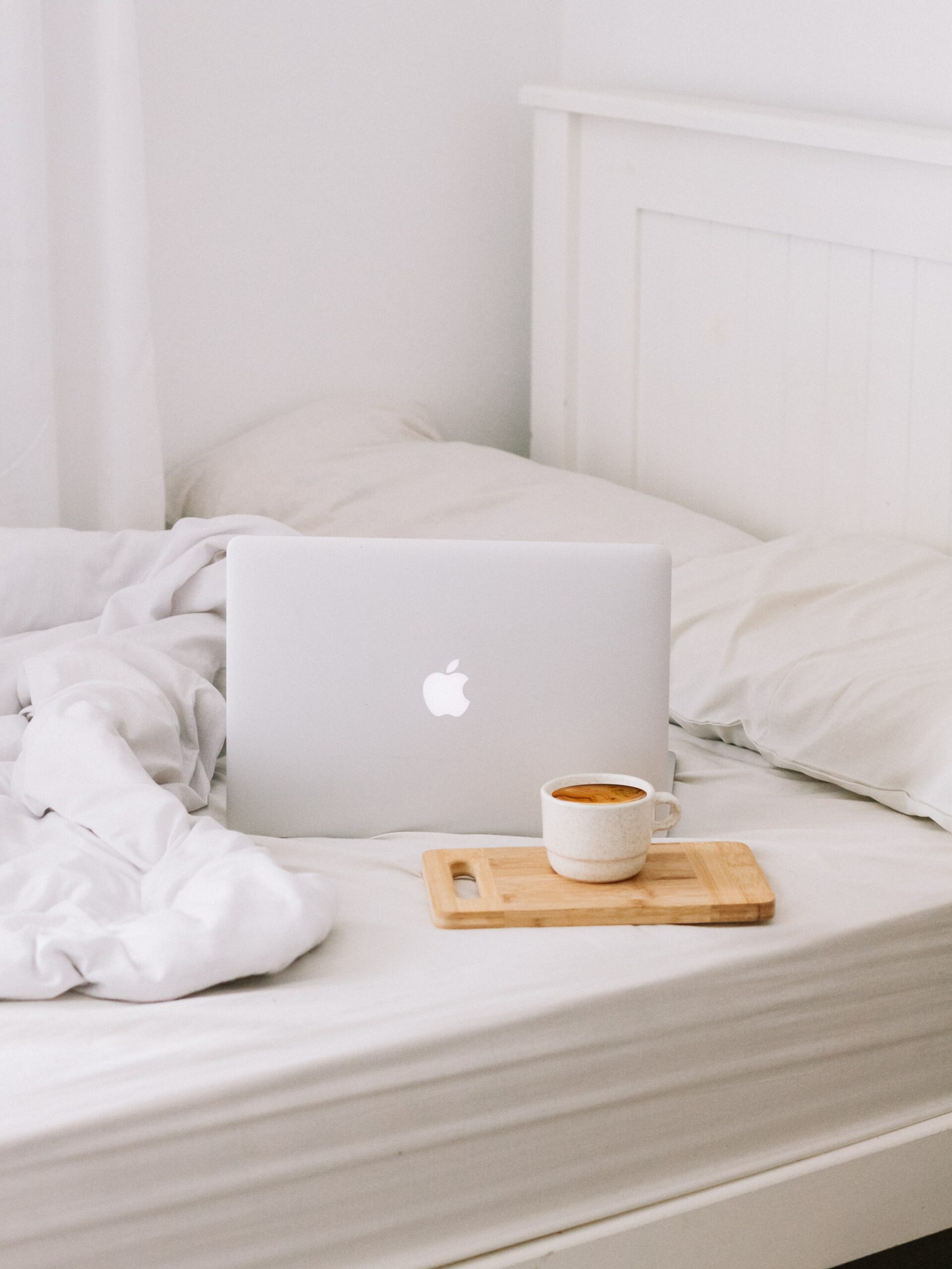מחשב של אפל על מיטה עם מגש כוס קפה ליד לבניית אתר בכיף